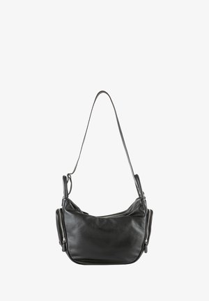 Sac en cuir noir porté à l'épaule avec une seule sangle et des poches latérales zippées, présenté sur un fond blanc.