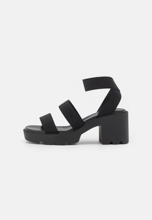 Sorte hælede sandaler med tre brede stofremme, en chunky blokhæl og en tekstureret sål for godt greb. Klassisk og minimalistisk design.