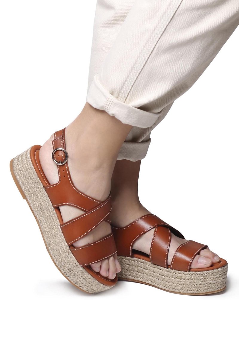 Sandali platform in pelle marrone con cinturini incrociati, un anello alla caviglia rotondo e suola in stile juta intrecciata, caratterizzati da una finitura liscia e cuciture leggere.