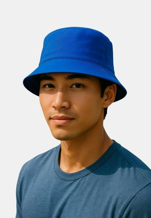 Blauwe bucket hat met een brede rand, gemaakt van zachte stof, gedragen door een persoon in een grijze shirt. Eenvoudig ontwerp, effen kleur en geen patronen.