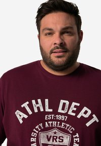 Bordeauxfarbenes T-Shirt mit kurzen Ärmeln aus Baumwolle. Verfügt über einen weißen, abgetragenen Druck mit "ATHL DEPT" und einem Emblemdesign. Runder Ausschnitt, lässige Passform.