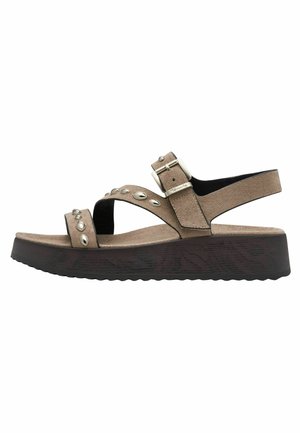 Brązowy zamszowy sandał z klamrą i wieloma okrągłymi metalowymi ozdobami, z ciemną platformą na koturnie o fakturze drewna i fakturowaną podeszwą.