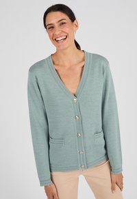 Cardigan verde chiaro con scollo a V, bottoni dorati e due tasche frontali. Tessuto lavorato a maglia e polsini a coste. Vestibilità casual, adatta per essere indossata a strati.