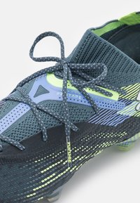 Scarpa da football in verde scuro con tomaia in maglia, dettagli verdi e accenti blu. Presenta texture intricate, lacci e motivi accattivanti.