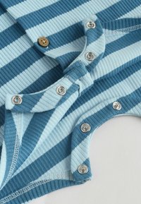 Tissu côtelé rayé bleu et bleu clair avec des boutons-pression en métal et un bouton cousu marron sur un vêtement pour bébé ou tout-petit.