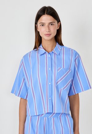 Short-sleeve, cropped shirt in light blue with vertical stripes in red and white. Features a button closure and a pocket on the left side.