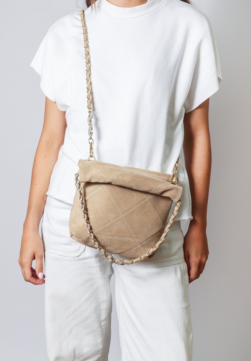 Borsa a tracolla in suede marrone con texture trapuntata, parte superiore pieghevole e una tracolla a catena. Presenta una forma morbida e arrotondata e un sottile dettaglio di cucitura.