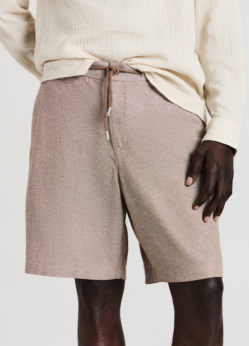Shorts marron clair en tissu texturé, avec une taille à cordon de serrage aux embouts argentés. Adaptés pour un usage décontracté.
