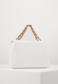 Vit, glänsande handväska med en strukturerad form och ett framträdande handtag i guldkedja. Slät textur, minimalistisk design, inga synliga mönster.