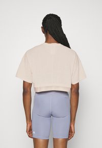 Jasnoróżowy krótki t-shirt z krótkimi rękawami, zestawiony z dopasowanymi jasnoniebieskimi szortami. Gładka faktura z prążkowanym dołem i detalem z logo.