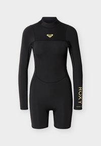 Combinaison courte noire à manches longues avec col montant, logo Roxy jaune sur la poitrine et texte "ROXY" jaune sur l'avant-bras gauche.