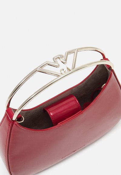Red leather handbag with a curved design, featuring a gold-tone metal handle and distinctive branding on the handle. Smooth texture.