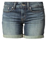 Farkkuhousut haalistuneessa sinisessä pesussa, joissa on kääritty helma, viisi taskua ja etunappi. Sileä rakenne näkyvillä ompeleilla.