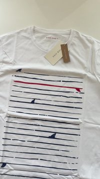 Weißes T-Shirt aus Bio-Baumwolle mit horizontalen blauen und roten Linien, die über die Vorderseite gedruckt sind. Mit Rundhalsausschnitt und angebrachten Markenetiketten.