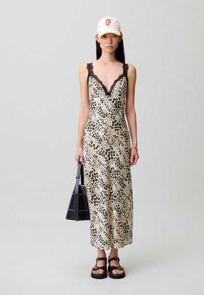 Vestido con estampado de leopardo, ribete de encaje negro, tirantes finos y silueta ajustada. Combinado con sandalias de plataforma y una gorra blanca. Bolso negro.