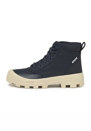 Bottines bleu foncé avec une tige texturée, semelles en caoutchouc crème et un motif de crampons distinctif. Présente des lacets et une tirette.