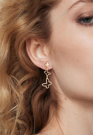 Złote kolczyki w kształcie motyla z warstwowym wzorem i błyszczącym wykończeniem. Lekkie, o otwartych kształtach i delikatnym wykończeniu.