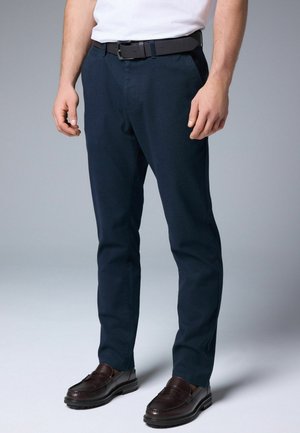 Navy blue trousers with a straight leg cut, made from smooth fabric. Paired with a black belt and brown loafers.