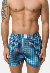 Boxers a cuadros en azul, negro y blanco con una cinturilla elástica, que cuentan con una abertura de botones y una etiqueta en la parte delantera. Material de algodón.