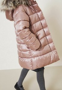 Chaqueta acolchada rosa con diseño acolchado y capucha con borde de piel. Presenta bolsillos laterales y un corte ligeramente acampanado. Material liso y brillante.