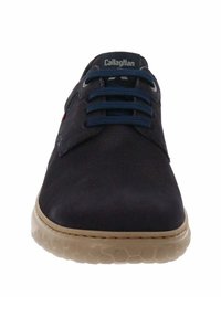 Zapato de piel de color azul marino oscuro con cordones, parte superior texturizada, cordones azules en contraste y suela de goma beige con un patrón de panal.