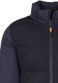 Gilet trapuntato blu navy con un tessuto testurizzato e sezioni lisce. Collo alto, zip frontale con accento arancione. Design leggero e aderente.