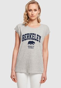 Hallinud lühikeste varrukatega hall puuvillane T-särk, millel on tumesinine graafika, mis kuvab teksti "BERKELEY" karu kohal ja "UNIVERSITY OF CALIFORNIA".
