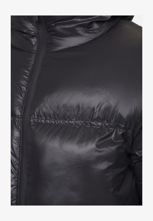 Zbliżenie na czarną pikowaną kurtkę o błyszczącej powierzchni, z kapturem i przednim zamkiem, z wytłoczonym logo "GOOD FOR NOTHING" na piersi.