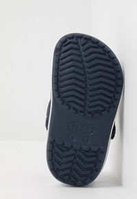 Tmavě modrá gumová podrážka boty s texturovaným vzorem pro lepší přilnavost, s oblým tvarem a zesílenou patou. Na podrážce je viditelná značka.