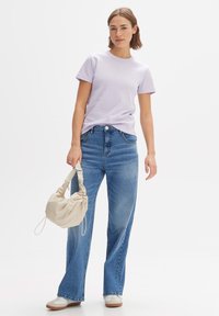 Lavender katoenen t-shirt met korte mouwen, gecombineerd met hoog-e taille blauwe jeans. Lichtbeige tas met een gegatherd detail en schouderband.