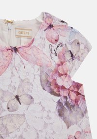 Witte kanten top met een bloemenpatroon en roze vlinders, verfijnde borduursels en een kleine ritssluiting aan de achterkant.