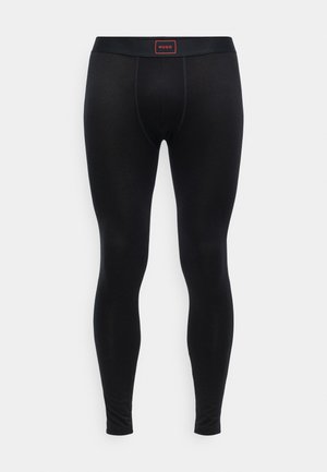 Schwarze Leggings aus einem glatten, dehnbaren Stoff. Der Bund hat ein rotes Etikett mit "HUGO". Sie sind figurbetont und haben keine sichtbaren Muster.