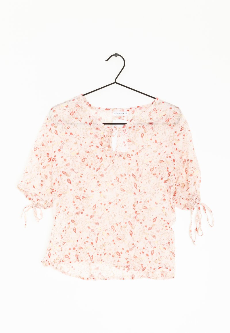 Blusa a maniche corte rosa con fantasia floreale, scollatura a chiave, legature arricciate sulle maniche e tessuto leggero e trasparente. Presenta motivi paisley e fiori.