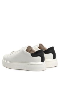 Białe skórzane sneakersy z czarną tylną łatą, okrągłym czubkiem i grubą białą gumową podeszwą. Posiadają sznurowanie i subtelne detale w postaci szwów.