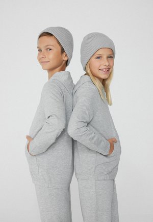 Zwei Kinder stehen Rücken an Rücken, tragen passende hellgraue Hoodies und Mützen. Der Stoff ist weich, mit einer glatten Textur und einem lässigen Schnitt.