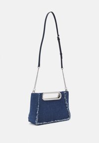 Denim handbag with a structured shape, dark blue color, frayed edges, silver hardware, and a chain strap. Features a top handle cutout.