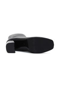 Botín negro de tacón alto con puntera redondeada, suela texturizada y tacón cuadrado. La parte superior es elegante y suave con un detalle mínimo.