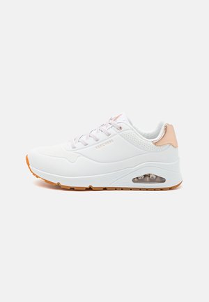 Chaussure de sport blanche avec une tige en maille et en synthétique, présentant un accent rose au niveau du talon, et une unité de coussin d'air visible dans la semelle.