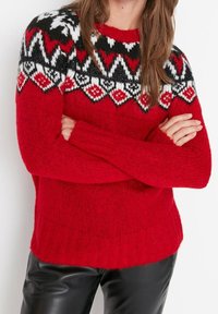 Rode gebreide trui met een gebloemde zwarte, witte en rode bies. Lange mouwen en ribgebreide manchetten met een relaxte pasvorm.