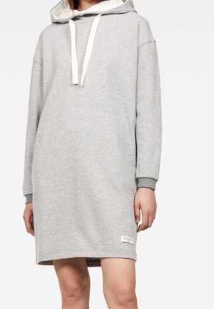 Abito felpa grigio con cappuccio, tasca a marsupio, stringhe bianche e polsini a costine. Tessuto liscio con una vestibilità casual e ampia.