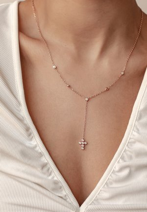 Kreuzanhänger aus Roségold mit klaren Edelsteinen, zarter Kette mit gleichmäßig verteilten Perlen und einem eleganten Tropfen-Design.