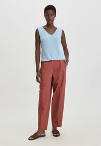 Lichtblauw gebreid tanktop met een V-hals, gecombineerd met roestkleurige wijde broek en bruine platte sandalen. Glad textuur, ontspannen pasvorm.