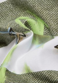 Strukturiertes Gewebe in Grün, Weiß und Blau mit floralem Muster; glatte, weiche Textur mit leichtem Design.