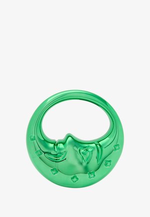 Szklany ozdobny element w kształcie półksiężyca z twarzą i gwiezdnymi detalami, wykonany z zielonego szkła, z gładką, lustrzaną powierzchnią.