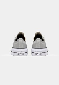 Šedé plátěné tenisky s bílou gumovou podrážkou, vyznačující se černým pruhem a označením "CONVERSE ALL STAR" na patě. Nízký střih.