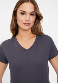 Camiseta de cuello en V de color gris oscuro, hecha de algodón suave, con mangas cortas y un diseño ajustado que presenta sutiles detalles de costura.