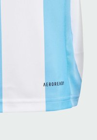 Jersey deportivo a rayas azul claro y blanco con tejido transpirable. Presenta el logo "AEROREADY" en la parte inferior izquierda. Textura suave.