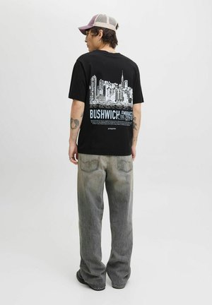 Sort grafisk t-shirt med print af en bylinje i hvid og blå. Parret med grå denimbukser, der har en afslappet pasform og en falmet struktur.