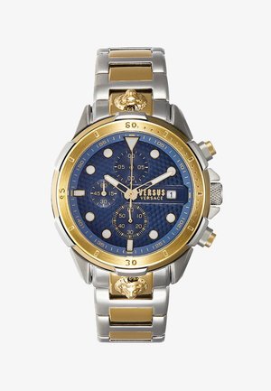Montre à cadran bleu avec accents dorés, bracelet en acier inoxydable et en ton or, sous-cadrans et détail de tête de lion sur le côté. Fonction chronographe visible.