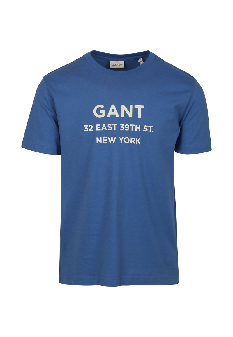 Blauw katoenen T-shirt met witte tekst: "GANT 32 EAST 39TH ST. NEW YORK." Korte mouwen en ronde halslijn, gladde textuur.